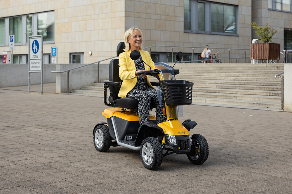 eine Frau in der Stadt unterwegs mit einem elektrischen Scooter von Mobilis in der Farbe Gelb