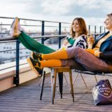 zwei Frauen mit guter Laune sitzen mit hochgelegten Füßen und tragen Kompressionsstrümpfe