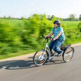 Frau auf einem Dreirad für Erwachsene in voller Fahrt