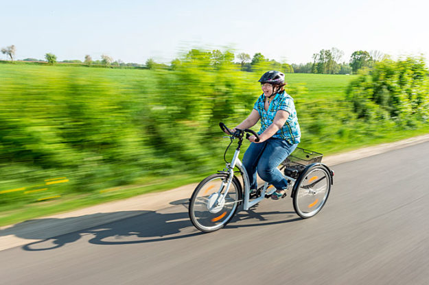 Frau auf einem Dreirad für Erwachsene in voller Fahrt