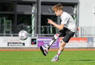 Junge mit Prothese am Bein spielt Fußball